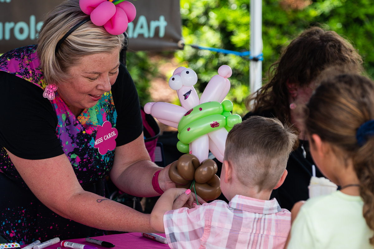 A woman gives children balloon animals