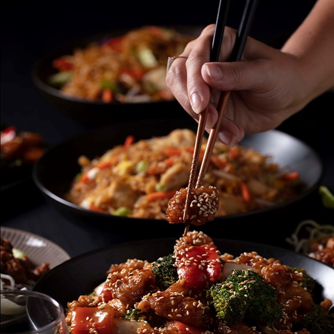 close up of chicken and broccoli being picked up by chop sticks